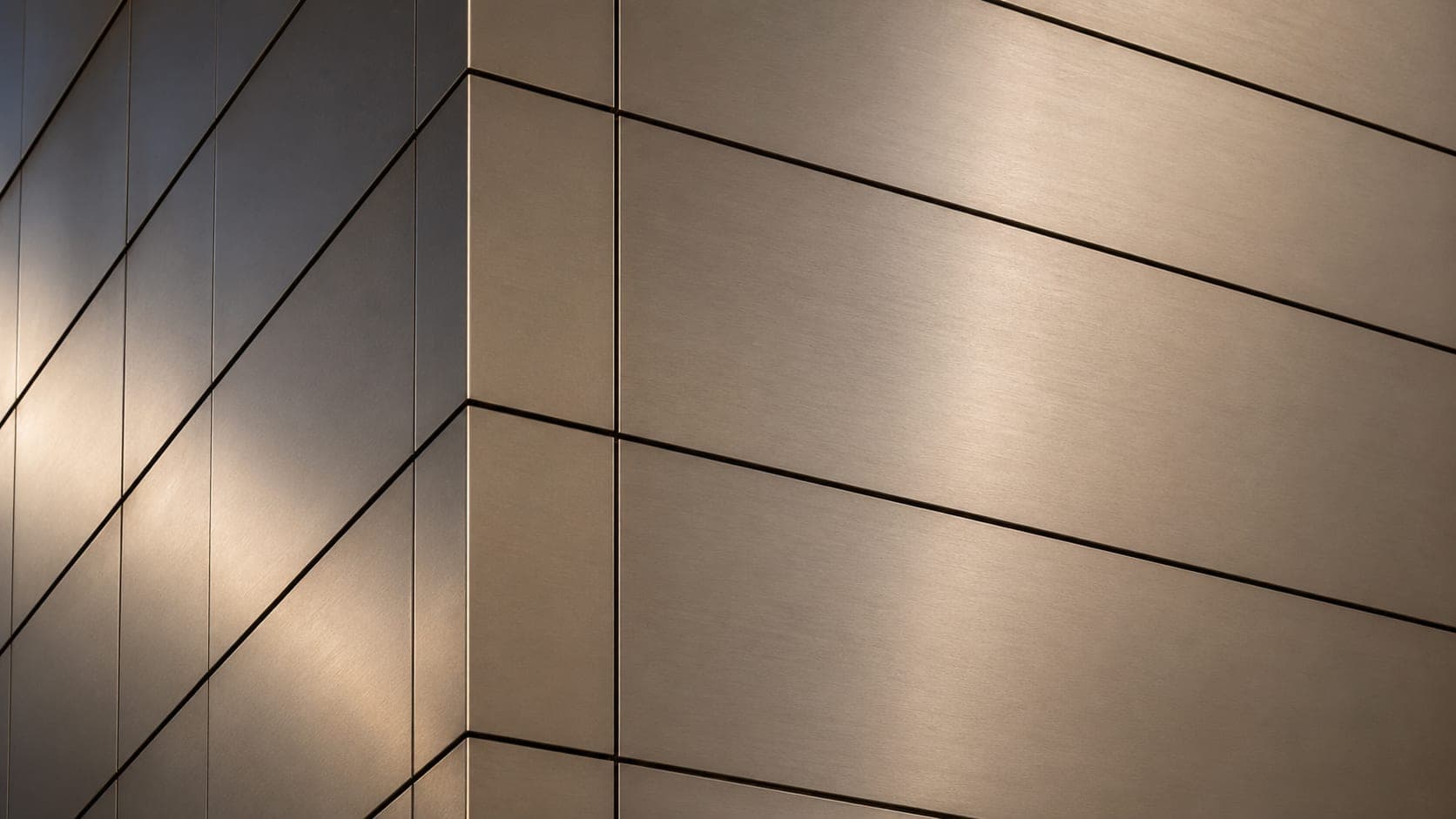 Close-up corner of a building clad in brushed bronze metal panels with visible seam lines, raking light