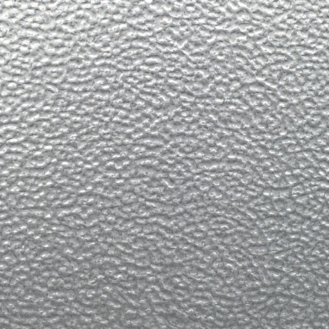 Extreme close-up of stucco-embossed aluminum surface showing a repeating pebble texture under raking light